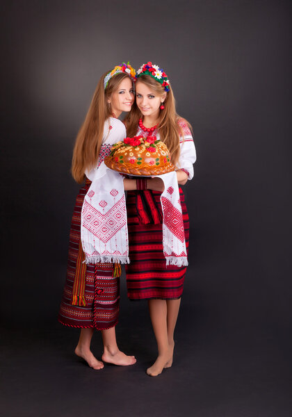 Young women in ukrainian clothes, with garland and round loaf