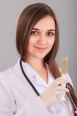Doktor kadın dolu bir şırınga tutarak