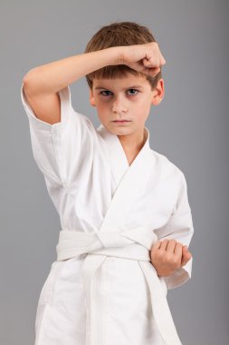 Beyaz kimonolu karateci çocuk dövüşüyor.