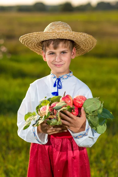 Glücklicher Bauernjunge hält Bio-Äpfel im herbstlichen Garten — Stockfoto