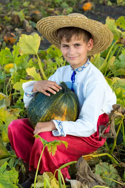 Улыбающийся мальчик держит в руках большую желтую тыкву. — стоковое фото