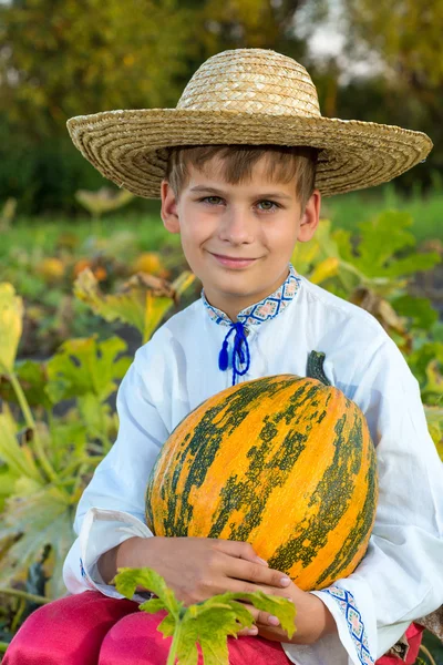 Smiling boy holding  big yellow pumpkin in hands — Stock Photo, Image