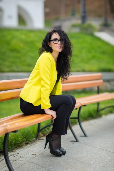 Bella ragazza è seduta su una panchina del parco — Foto Stock