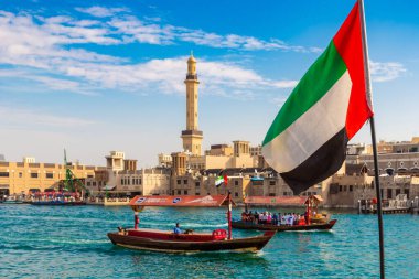 DUBAI, BAE - 5 Nisan 2020: Birleşik Arap Emirlikleri bayrağı Abra 'ya karşı - Birleşik Arap Emirlikleri' nin Dubai Körfezi 'ndeki eski geleneksel ahşap tekne