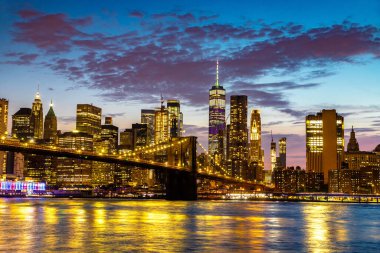 Brooklyn Köprüsü 'nün günbatımı ve New York City, ABD' deki Manhattan şehir merkezinin panoramik manzarası.