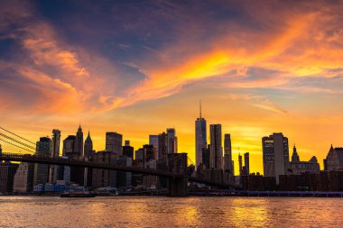 Brooklyn Köprüsü 'nün günbatımı ve New York City, ABD' deki Manhattan şehir merkezinin panoramik manzarası.