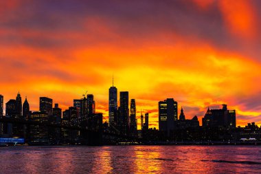 Brooklyn Köprüsü 'nün günbatımı ve New York City, ABD' deki Manhattan şehir merkezinin panoramik manzarası.