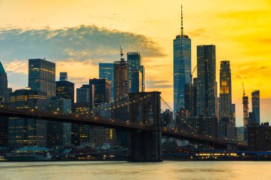 Brooklyn Köprüsü 'nün günbatımı ve New York City, ABD' deki Manhattan şehir merkezinin panoramik manzarası.