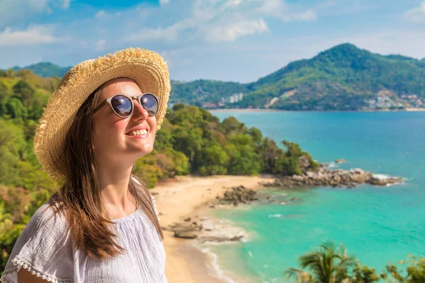 Güneşli bir günde Tayland 'ın Phuket Adası' ndaki Laem Sing plajının panoramik hava manzarasında mavi elbise ve hasır şapka giyen kadın gezgin.