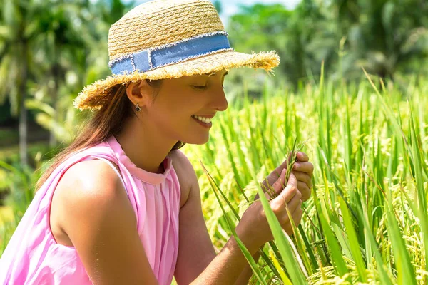 穿着粉色连衣裙 头戴草帽的女旅行家把稻种放在田里 — 图库照片