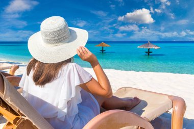 Güneşli bir yaz gününde lüks bir tropik plajda güneşlenen güzel bir kadın.