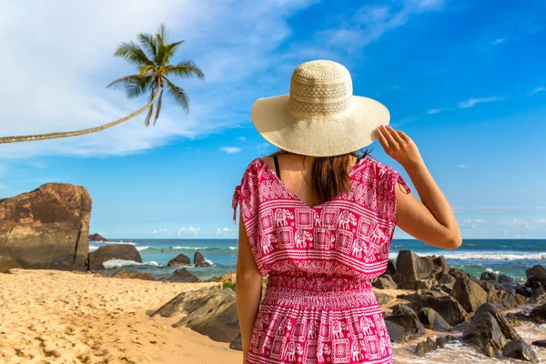 海の近くの熱帯のビーチに滞在帽子と赤いドレスを身に着けている若い美しい女性の肖像画 — ストック写真