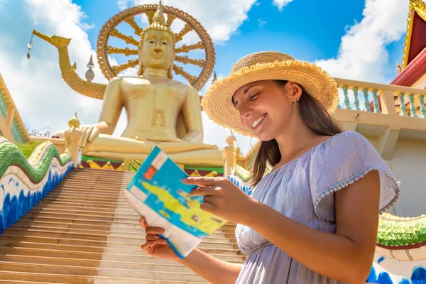 青いドレスと藁帽子を身に着けている女性旅行者は 夏の日にタイのサムイ島の大仏で地図を保持します — ストック写真