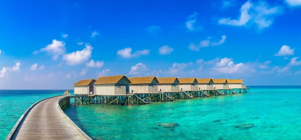 Panorama of  Water Villas (Bungalows) and wooden jetty at Tropical beach in the Maldives at summer day