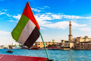 Abra 'ya karşı Birleşik Arap Emirlikleri bayrağına odaklan. Eski ahşap tekne ve Dubai Körfezi' ndeki Dubai Mescidi Camii.