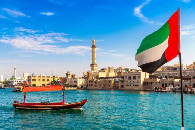 Abra 'ya karşı Birleşik Arap Emirlikleri bayrağına odaklan. Eski ahşap tekne ve Dubai Körfezi' ndeki Dubai Mescidi Camii.