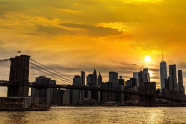 Brooklyn Köprüsü 'nün günbatımı ve New York City, ABD' deki Manhattan şehir merkezinin panoramik manzarası.