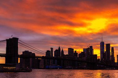 Brooklyn Köprüsü 'nün günbatımı ve New York City, ABD' deki Manhattan şehir merkezinin panoramik manzarası.