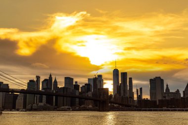 Brooklyn Köprüsü 'nün günbatımı ve New York City, ABD' deki Manhattan şehir merkezinin panoramik manzarası.