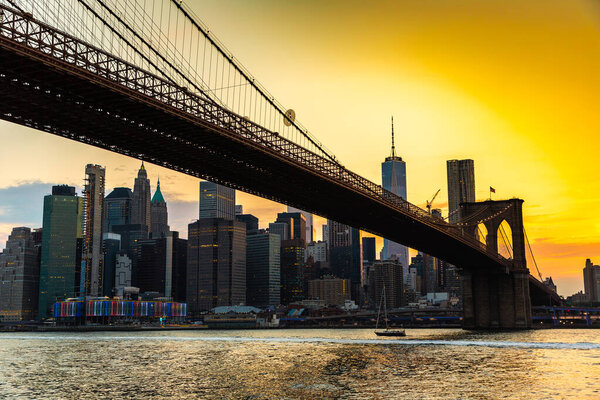 Sunset view of Brooklyn Bridge and panoramic view of downtown Manhattan in New York City, USA