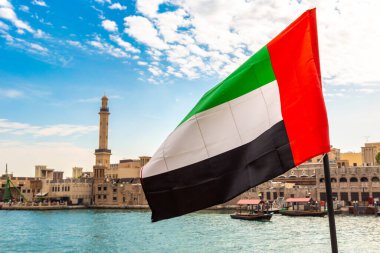 Abra 'ya karşı Birleşik Arap Emirlikleri bayrağına odaklan. Eski ahşap tekne ve Dubai Körfezi' ndeki Dubai Mescidi Camii.