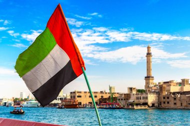 Abra 'ya karşı Birleşik Arap Emirlikleri bayrağına odaklan. Eski ahşap tekne ve Dubai Körfezi' ndeki Dubai Mescidi Camii.