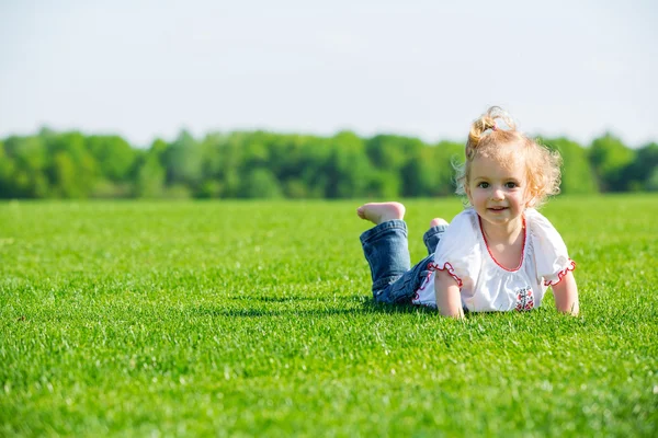 Pequena menina feliz em uma grama — Fotografia de Stock