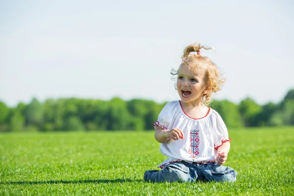 Pequena menina feliz em uma grama — Fotografia de Stock