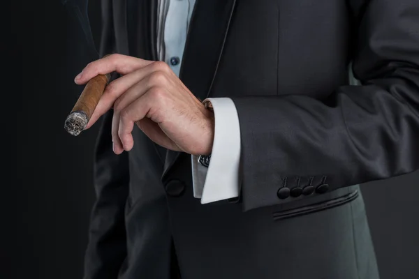 Man in a black suit holding a cigar in a left hand — Stock Photo, Image