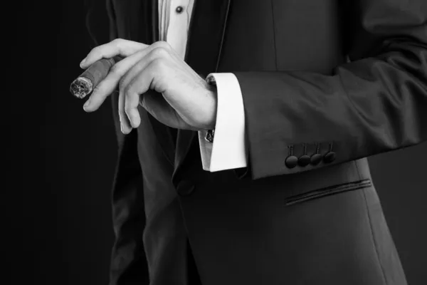 Man in a black suit holding a cigar in a left hand — Stock Photo, Image