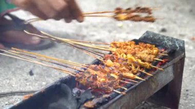 Geleneksel Endonezya sokak yemekleri, tavuk satay, geleneksel kömür ateşiyle hazırlanmış. Eller satay pişiriyor. 