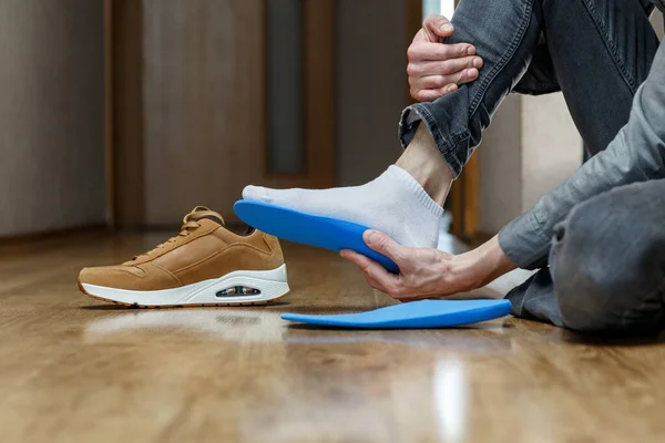 男は新しいカスタムインソールを靴に入れて 足のレクリエーション医学の概念 — ストック写真