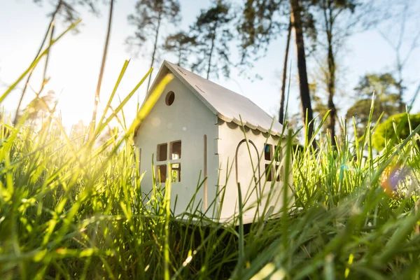 Model of a white wooden house on a green grass lawn.  Eco house development concept.