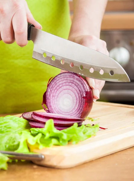 Woman\'s hands cutting bulb onion