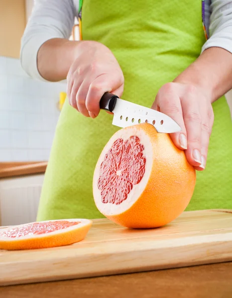 Woman's hands cutting grapefruit — Stock Photo, Image