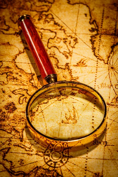 Vintage magnifying glass lies on an ancient world map — Stock Photo, Image