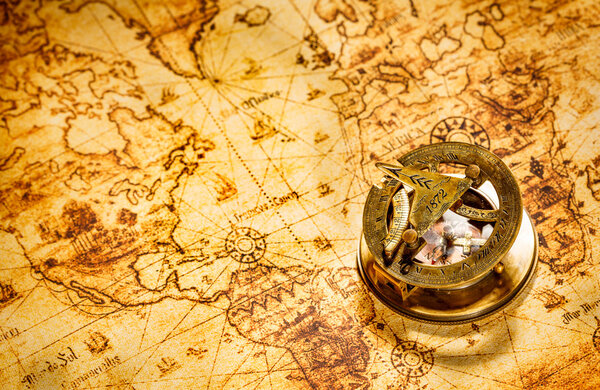 Vintage compass lies on an ancient world map.
