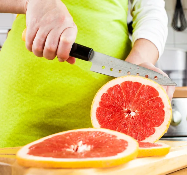 Ženské ruce řezání grapefruitu — Stock fotografie