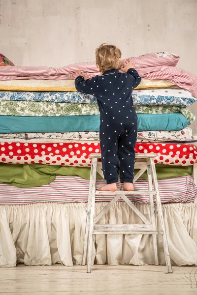 Child climbs on the bed - Princess and the Pea. — Stock Photo, Image