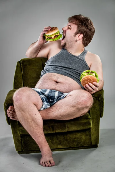 Fat man eating hamburger — Stock Photo, Image