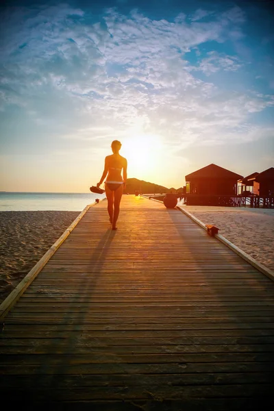 一个女孩在日落时分沿着码头走的剪影 — 图库照片