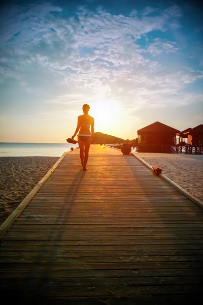 Silhouet van een meisje, wandelen langs de pier bij zonsondergang — Stockfoto