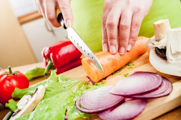 Mains de femme coupant des légumes — Photo