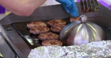 Et köftesi sıcak bir kızartma tavasında pişirilir. Sokak yemekleri, şef spatulayla hamburger çeviriyor..