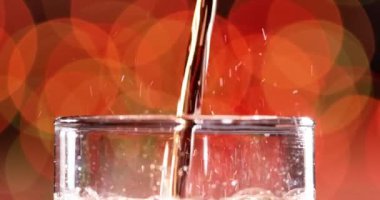 Bir bardak kola. Bulanık ışık ve bulanık arkaplan üzerinde su sıçratan baloncuklu buzlu kola yavaş çekim.