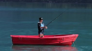 Teknedeki kadın Norveç 'te dönerken balık yakalar. Norveç 'te balık tutmak yerel yaşam tarzını benimsemenin bir yoludur. Sayısız göl ve nehirler ve geniş bir kıyı şeridi olağanüstü fırsatlar demektir.