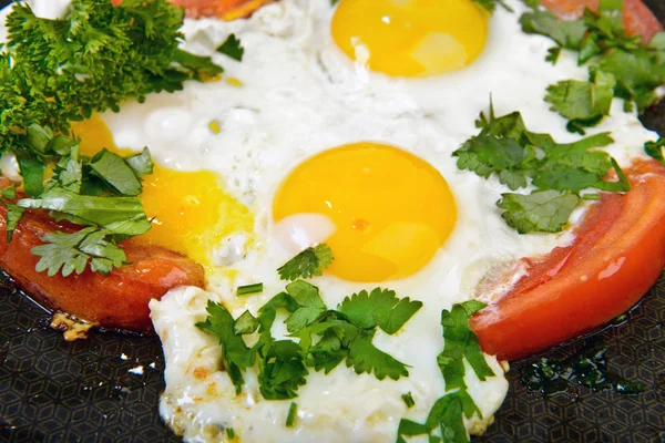 Fried eggs and tomato on pan — Stock Photo, Image