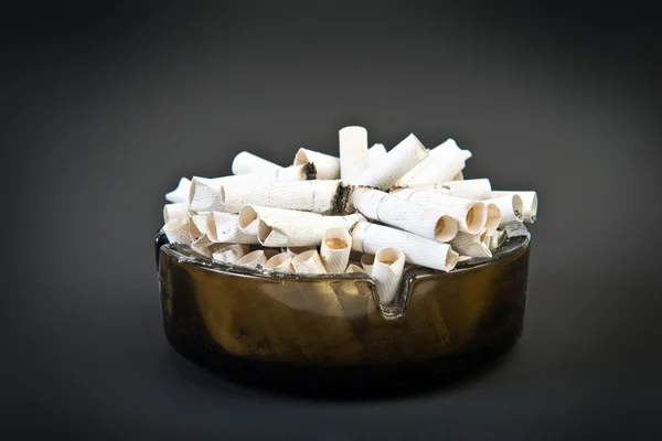 Full ashtray with butts over black — Stock Photo, Image