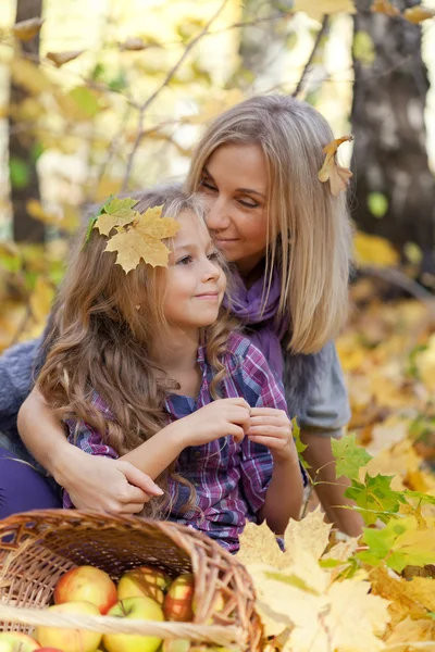 Happy mum and the daughter play autumn park on the fallen down foliage