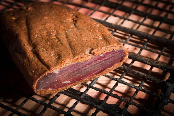木のテーブルの上のワイヤーラックの上で燻製肉 — ストック写真